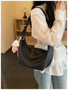 Stylish black hobo shoulder bag for women, soft leather dumpling bag with cute bear charm.