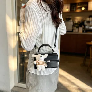 Chic black PU leather crossbody bag featuring a cute plush bear pendant and retro top handle design.