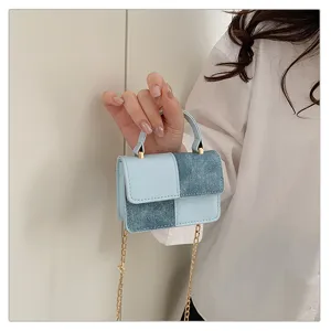 Closeup of mini patchwork crossbody bag, blue denim and leather texture with gold chain.
