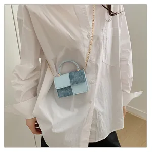 Detailed view of fashionable blue denim patchwork mini crossbody bag with gold chain strap.