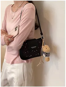 Black star pattern underarm shoulder bag with cute bear pendant for women fashion daily use.