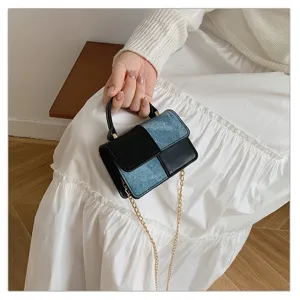 Detailed view of a chic color-blocked mini shoulder bag with top handle and gold chain detail