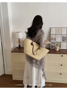 Vue détaillée du sac cabas en paille tressée vintage, doté de poignées en cuir solides.
