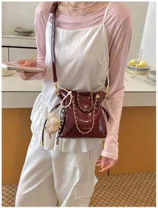 Burgundy quilted shoulder bag detail, elegant chain strap and chic plush charm design.
