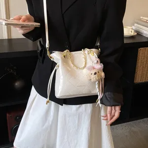 White quilted shoulder bag with chain strap and cute plush bear charm for women daily commuting.