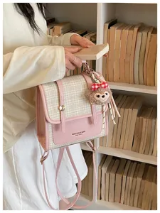 Pink plaid backpack detail view, featuring cute plush charm and elegant dual-use strap design.