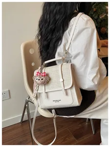 Detail view of the stylish color-block patchwork women's shoulder bag with cute plush charm.