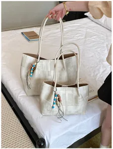 Detailed view of the casual newspaper print tote bag with beaded charm in lifestyle setting.