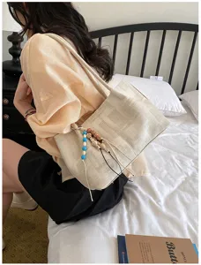 Detailed view of casual canvas shoulder bag, stylish Korean design with beaded charm pendant.