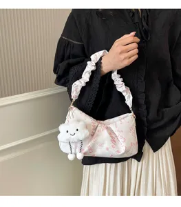 Primo piano dettagliato della borsa a tracolla bianca elegante con ciondolo peluche e stampe.