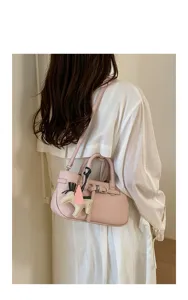 Pink leather shoulder bag detail, stylish women's crossbody handbag with cute charm accessory.