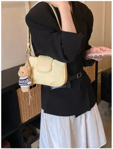 Yellow underarm shoulder bag detail with cute bear pendant and star pattern design.