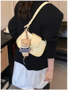Stylish yellow women shoulder bag with cute bear pendant, trendy underarm daily handbag.