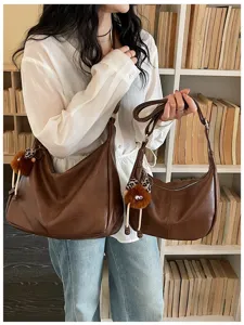 Casual brown shoulder bag detail shot showing large capacity, soft leather and cute charm.
