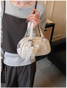 Detail view of white bowling handbag featuring elegant pearl bow detail and compact design.