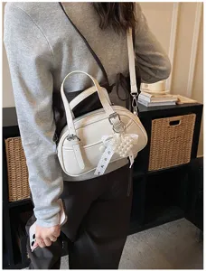 Stylish white bowling shoulder bag for women, versatile crossbody purse with cute pearl bow charm.