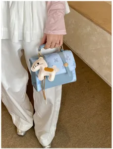 Chic light blue handbag detail, featuring cute horse charm and elegant hardware for daily use.