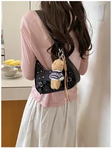 Detail shot of a retro black underarm shoulder bag with star print, bow and cute bear pendant.