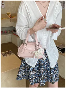 Detailed view of a chic pink bowling handbag with pearl lace pendant and double buckle design.