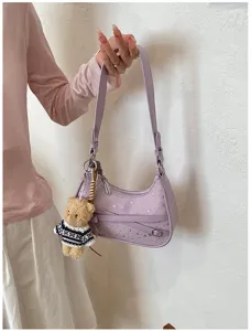 Purple shoulder bag with silver star studs and cute bear pendant, stylish daily accessory.