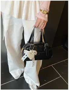 Close-up detail of the stylish black patent leather bowling handbag featuring pearl lace charm.