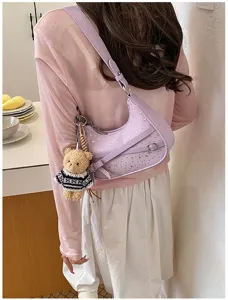 Detailed view of trendy purple shoulder bag with star studs and cute bear pendant detail.