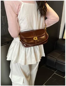 Vue de détail du sac bandoulière en cuir vernis marron vintage avec fermoir doré.