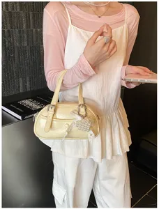 Cream yellow bowling handbag detail, glossy PU leather crossbody purse with pearl ribbon pendant.
