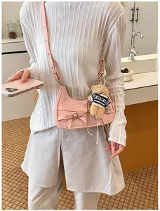Detail shot of pink shoulder hobo bag with bow and cute bear charm for daily commute.