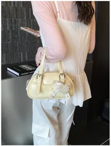 Detail view of a trendy yellow bowling handbag featuring a sweet pearl heart pendant.