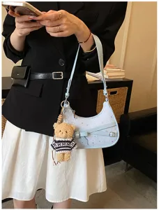 Detail view of light blue crescent shoulder bag with star pattern and cute plush bear charm.