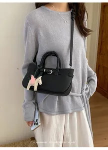 Stylish black leather crossbody handbag with chic metal buckle and cute pegasus charm detail.