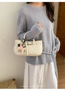 Minimalist pebbled leather handbag with cute horse charm, chic retro shoulder bag style.