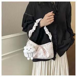 Vista dettagliata della borsa a mano bianca con stampa rosa, manico arricciato e ciondolo.
