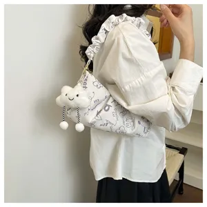 Vista dettagliata di una borsa a tracolla bianca con stampa di gatti e ciondolo a forma di nuvola.