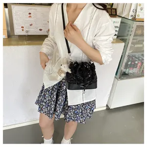 Detail view of the stylish black bucket handbag featuring star patterns and cute plush pendant.