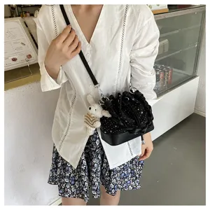 Detailed view of a trendy black star print bucket bag with braided strap and cute plush pendant.