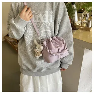 Detailed view of the purple pleated bucket bag with braided handle and cute bear charm.