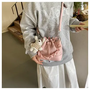 Detailed view of the cute pink bucket bag featuring a braided handle and bunny pendant.