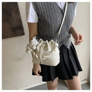 Stylish white bucket bag for women with woven handle and cute bear pendant charm.