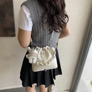 Stylish women's white bucket bag, trendy pleated crossbody shoulder bag with cute bear charm.