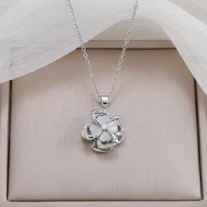 Close-up detail of silver rotating four-leaf clover necklace with sparkling white stones.