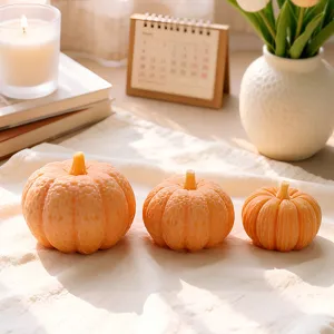 Set of three cute orange pumpkin scented candles for cozy autumn home decor and holidays.