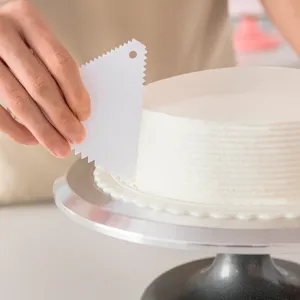Plastic cake scraper tool with serrated edges for smooth frosting and baking decoration.