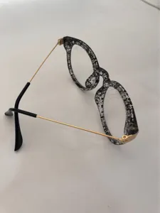 Close-up detail of vintage retro optical glasses frame, black white splatter acetate metal.