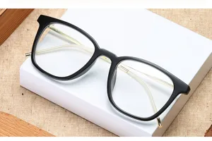 Closeup of vintage black frame optical glasses with slim gold metal temples on white box.