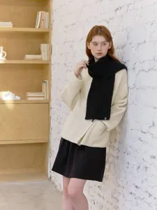 Cozy wool-blend cable knit scarf in solid black, worn by a model in a lifestyle detail shot.