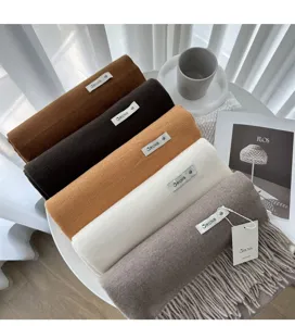 Detail view of solid color cashmere scarf roll with brand tag, cozy winter fashion accessory.