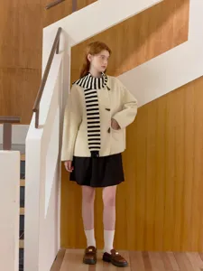 Detailed view of the stylish striped knit scarf and beige coat outfit, perfect for casual wear.