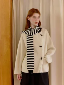 Detailed view of creative black and white striped knitted scarf paired with elegant outerwear.